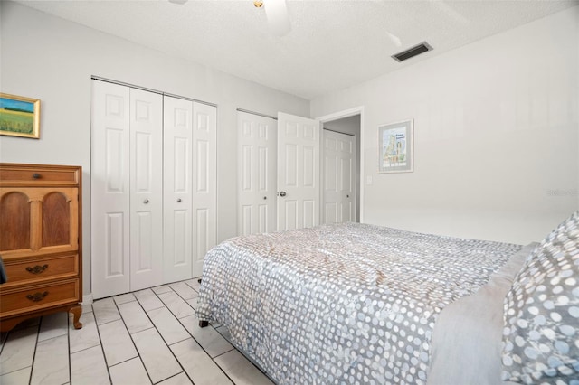 tiled bedroom featuring multiple closets and a textured ceiling