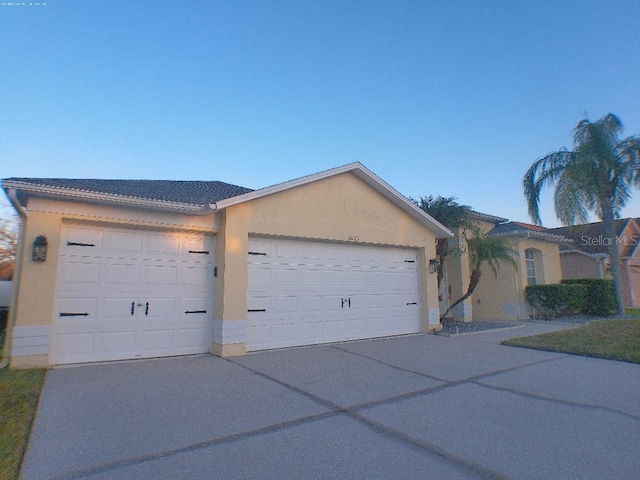 view of front of house featuring driveway, an attached garage, and stucco siding