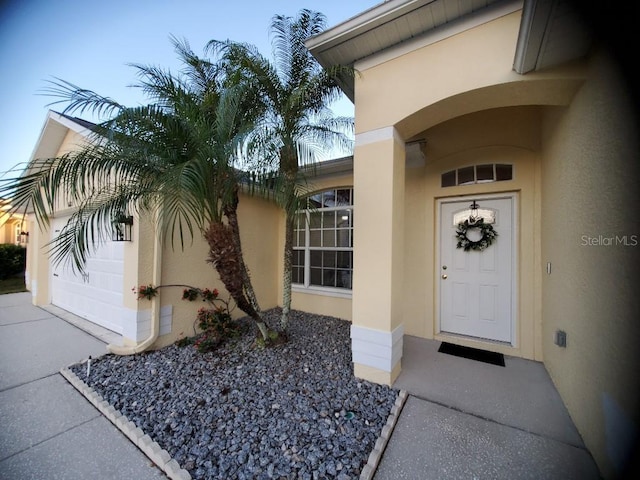 property entrance with a garage and stucco siding