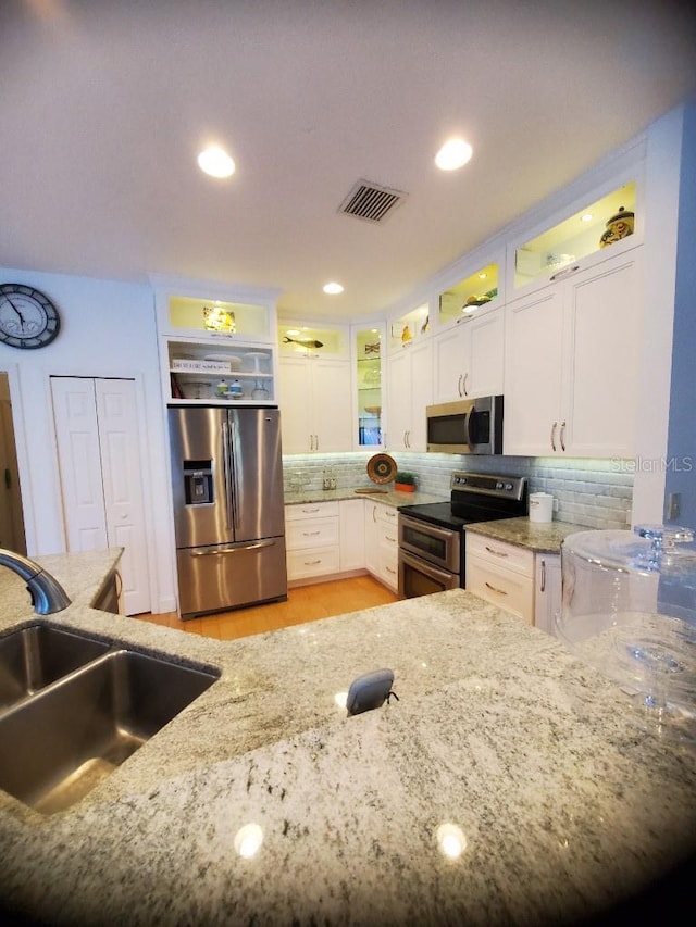 kitchen with appliances with stainless steel finishes, backsplash, visible vents, and white cabinets