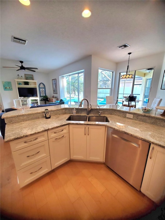 kitchen with visible vents, light stone countertops, stainless steel dishwasher, pendant lighting, and a sink