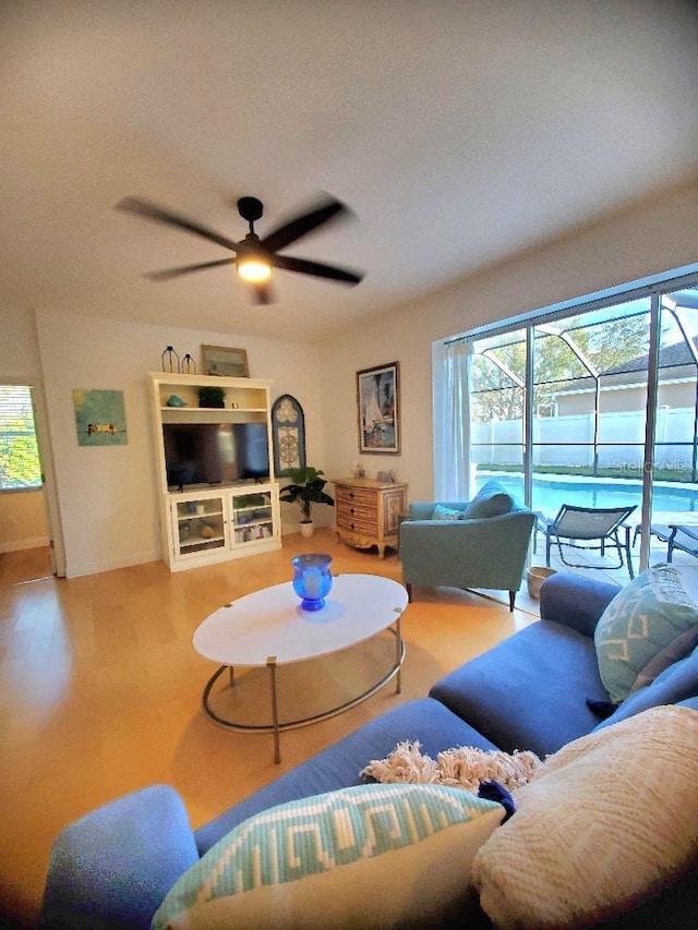 living area with a ceiling fan, a sunroom, and wood finished floors