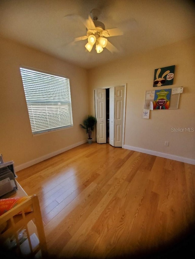 unfurnished bedroom with light wood-style floors, a closet, ceiling fan, and baseboards