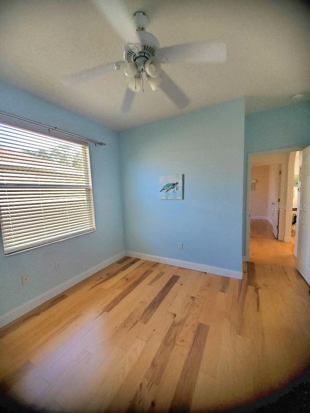 spare room featuring light wood-style floors, ceiling fan, and baseboards