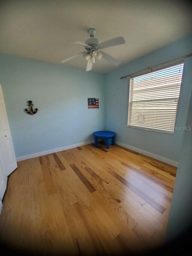 unfurnished bedroom with wood finished floors, a ceiling fan, and baseboards