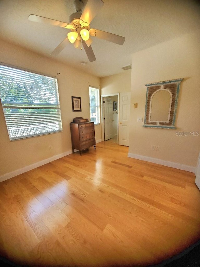 unfurnished bedroom with baseboards, a ceiling fan, and light wood-style floors