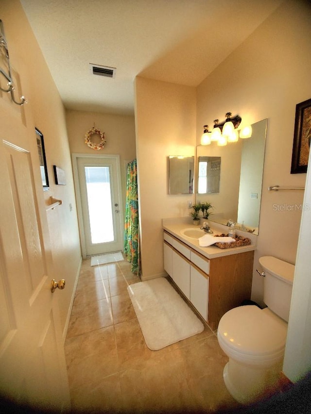 bathroom featuring baseboards, visible vents, toilet, tile patterned floors, and vanity