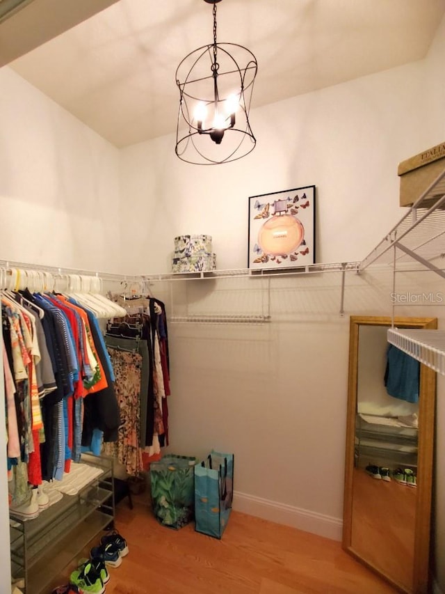 spacious closet with a chandelier and wood finished floors