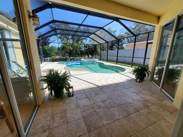 view of pool with a patio, glass enclosure, fence, and a pool with connected hot tub