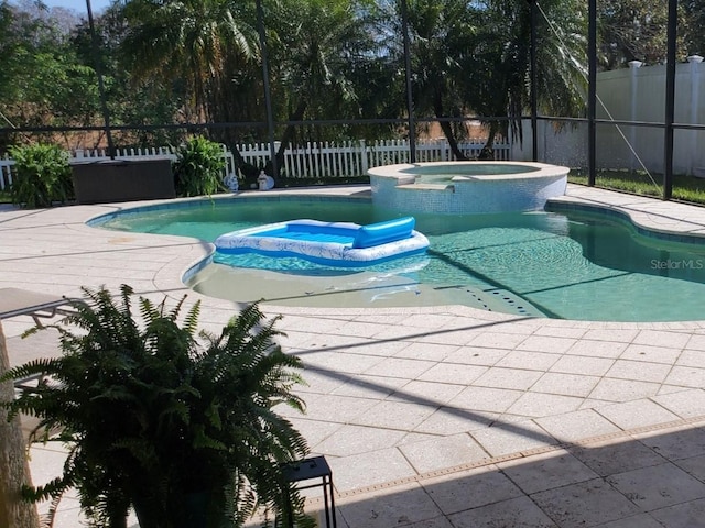 view of pool featuring glass enclosure, a patio, a fenced backyard, and a pool with connected hot tub