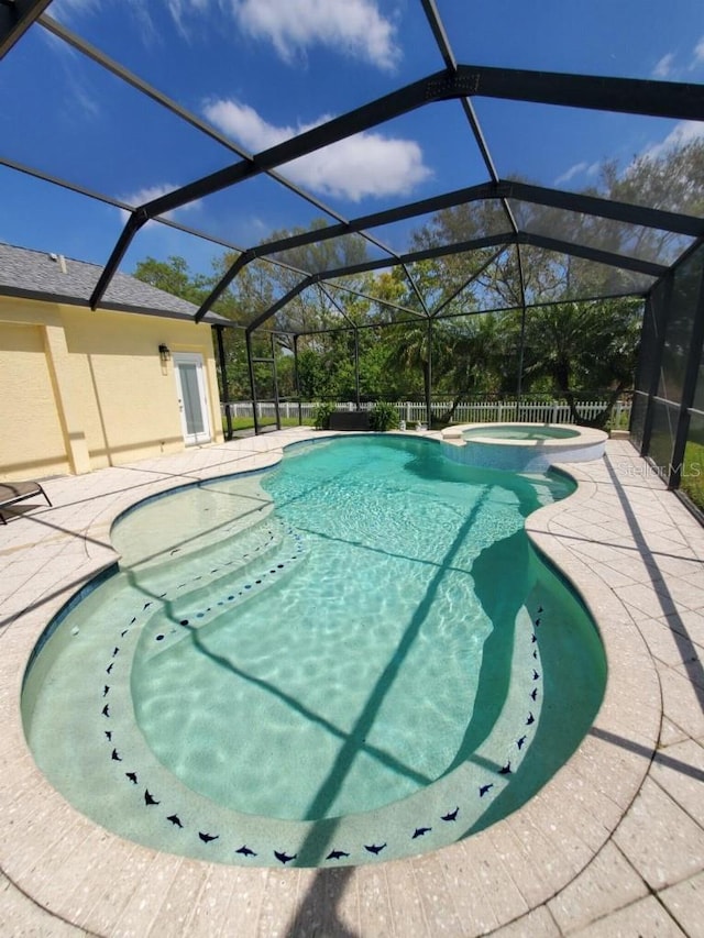 view of swimming pool with glass enclosure, a patio, and a pool with connected hot tub