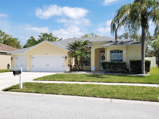 ranch-style home with concrete driveway, a garage, a front yard, and stucco siding