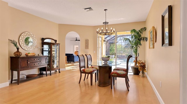 dining space featuring visible vents, ceiling fan with notable chandelier, light wood-type flooring, and baseboards