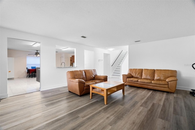 living room with ceiling fan, wood-type flooring, and a textured ceiling