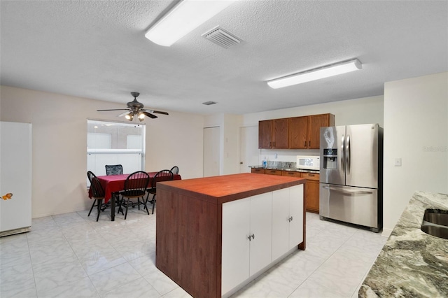 kitchen with sink, white appliances, ceiling fan, a center island, and a textured ceiling