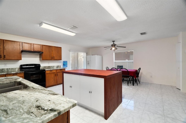 kitchen with a textured ceiling, black range with electric cooktop, a kitchen island, ceiling fan, and white refrigerator with ice dispenser