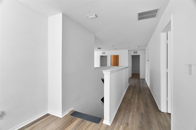 corridor with hardwood / wood-style floors and a textured ceiling