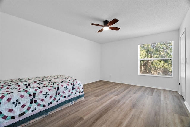 bedroom with ceiling fan, light hardwood / wood-style flooring, and a textured ceiling