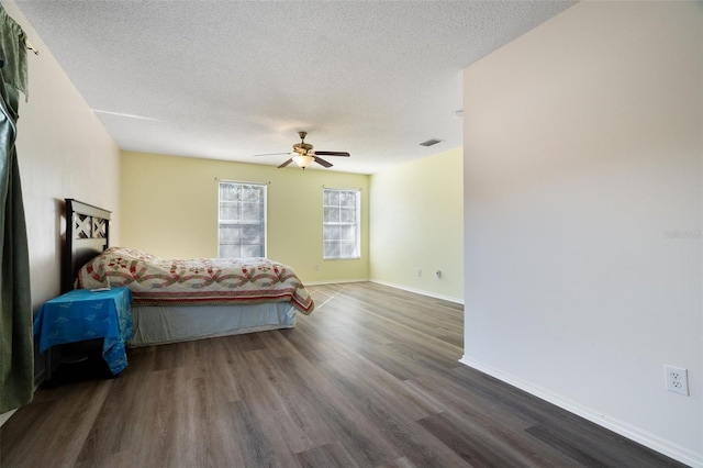 bedroom with a textured ceiling, dark wood-type flooring, and ceiling fan