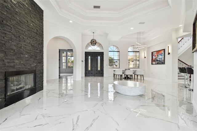 foyer featuring ornamental molding, a tray ceiling, and a high ceiling