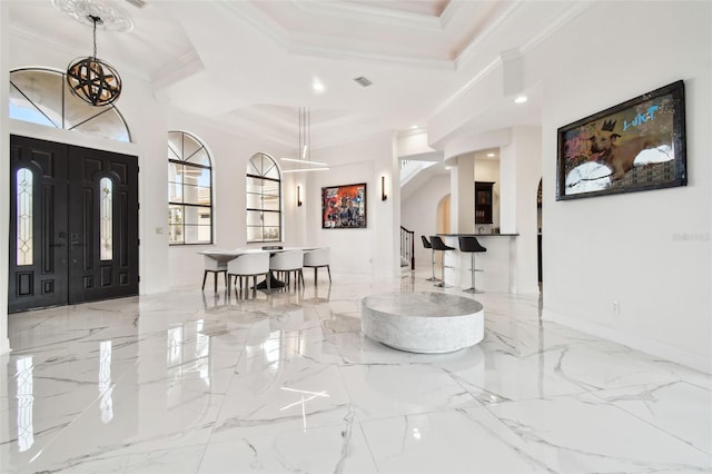 foyer with a high ceiling, ornamental molding, and a chandelier