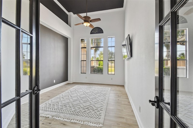 interior space with french doors, ceiling fan, light hardwood / wood-style floors, and a high ceiling