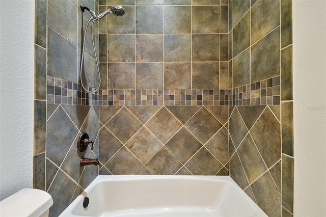 bathroom with tiled shower / bath and toilet