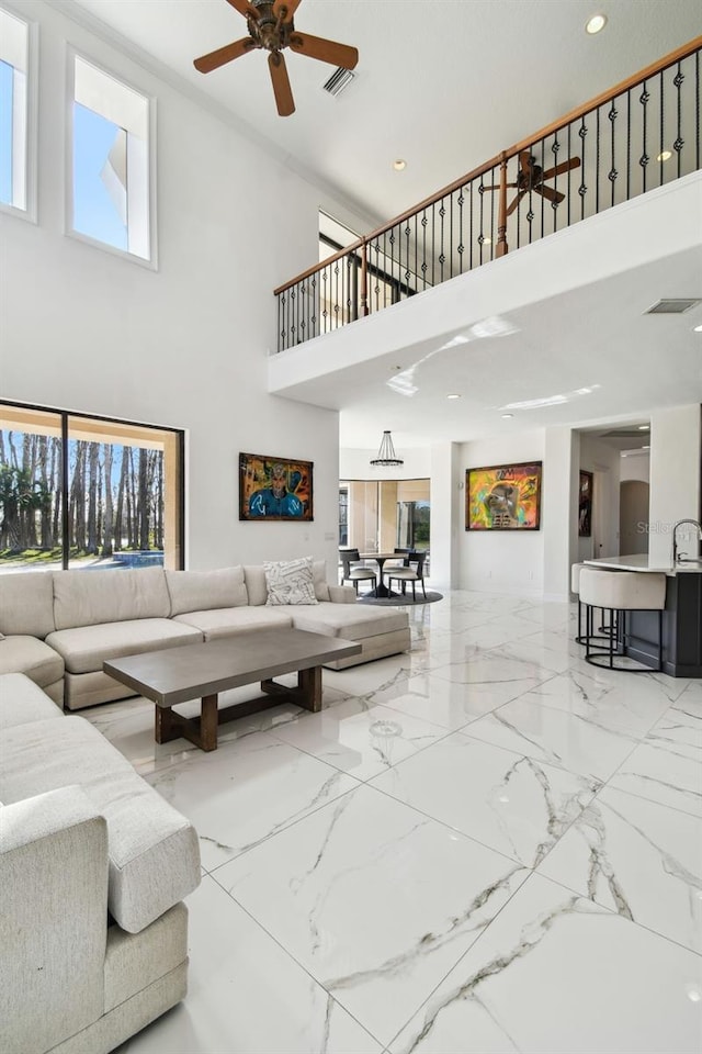 living room featuring a towering ceiling, a wealth of natural light, and ceiling fan