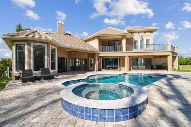 rear view of house featuring a swimming pool with hot tub, a patio area, and ceiling fan