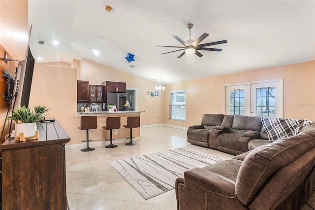 living room with ceiling fan with notable chandelier, lofted ceiling, sink, and french doors