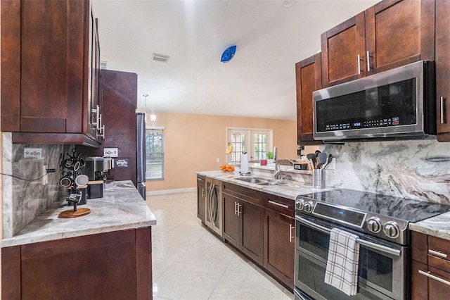 kitchen featuring appliances with stainless steel finishes, tasteful backsplash, sink, light stone counters, and french doors