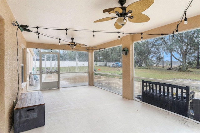 unfurnished sunroom featuring rail lighting and ceiling fan