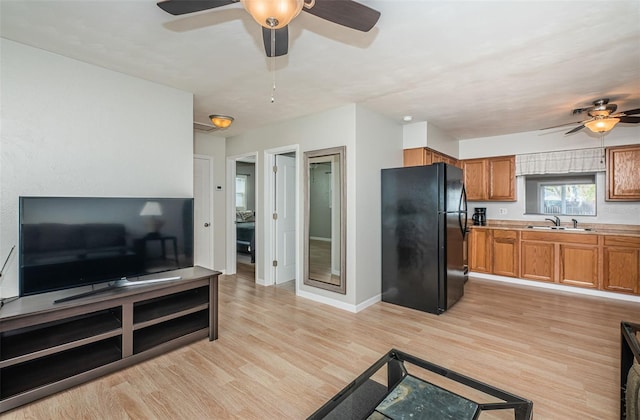 living room featuring sink, light hardwood / wood-style floors, and ceiling fan