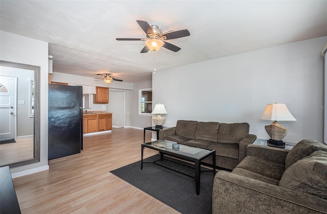 living room with sink, light hardwood / wood-style flooring, and ceiling fan