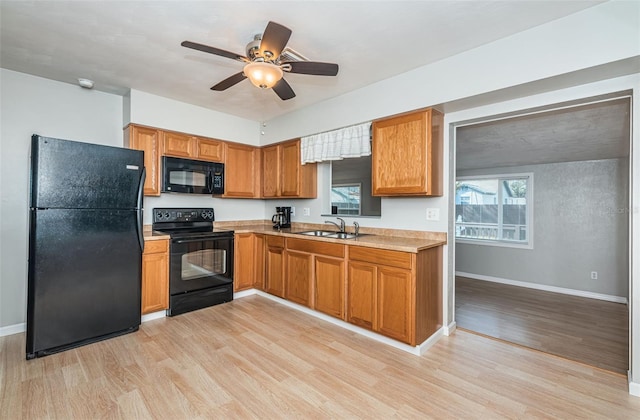 kitchen with sink, black appliances, light hardwood / wood-style floors, and ceiling fan