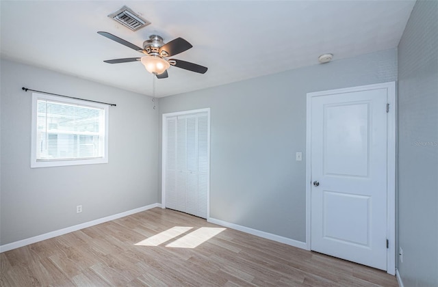 unfurnished bedroom featuring ceiling fan, light hardwood / wood-style floors, and a closet