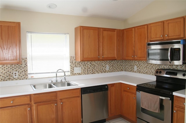 kitchen featuring stainless steel appliances, lofted ceiling, sink, and decorative backsplash