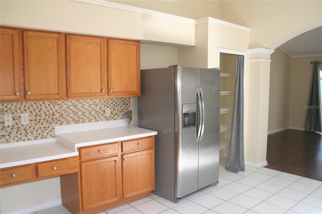 kitchen with crown molding, backsplash, light tile patterned floors, and stainless steel fridge