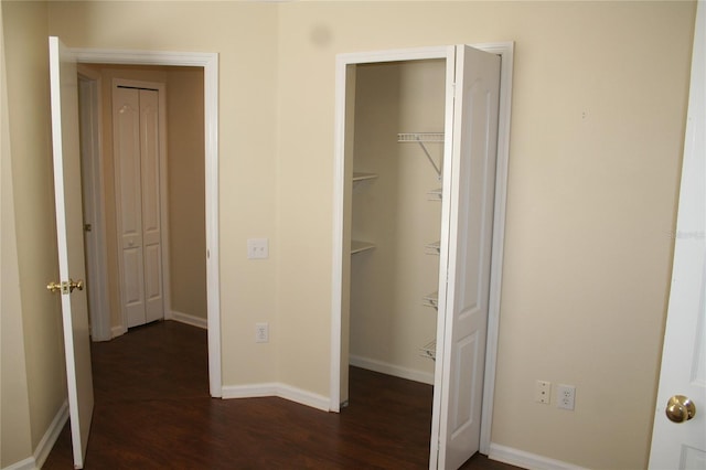 unfurnished bedroom with a walk in closet, dark hardwood / wood-style floors, and a closet