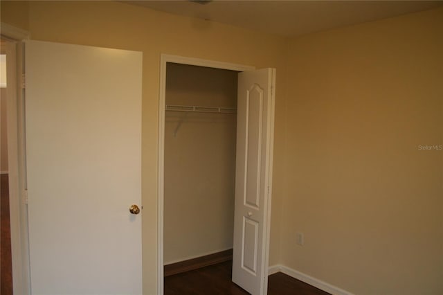 unfurnished bedroom with dark hardwood / wood-style flooring and a closet