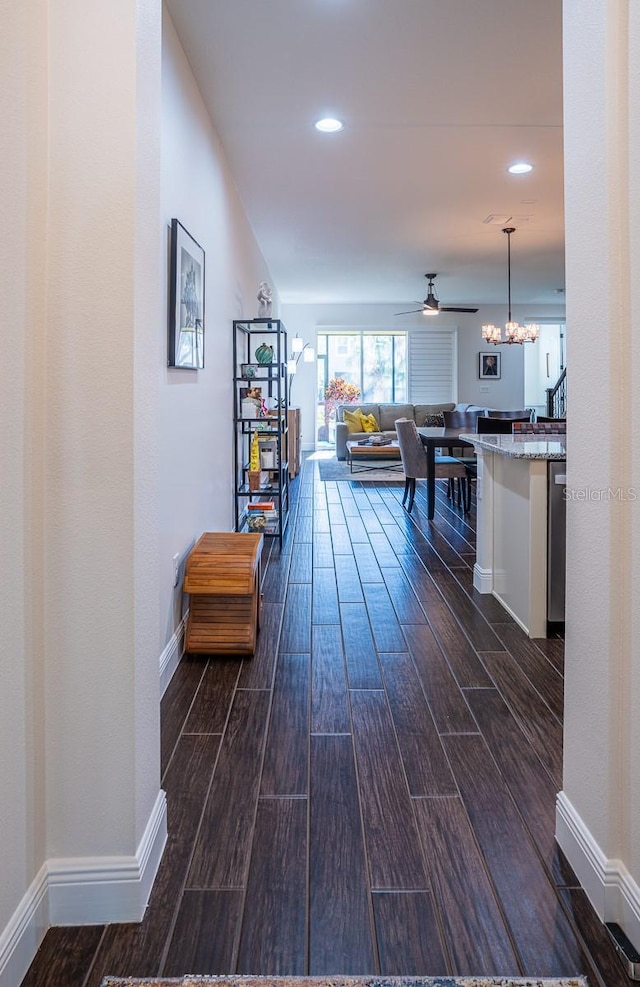 hall featuring dark wood-type flooring and a notable chandelier