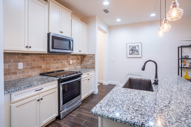 kitchen with sink, white cabinetry, light stone counters, a center island with sink, and stainless steel appliances