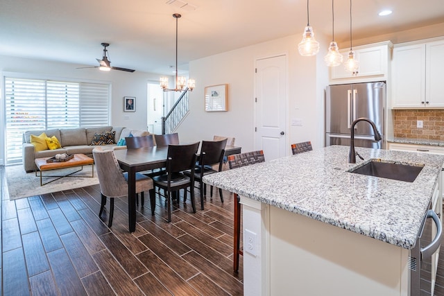 kitchen featuring sink, a breakfast bar, white cabinetry, an island with sink, and high end refrigerator