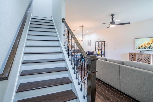 stairs featuring ceiling fan with notable chandelier