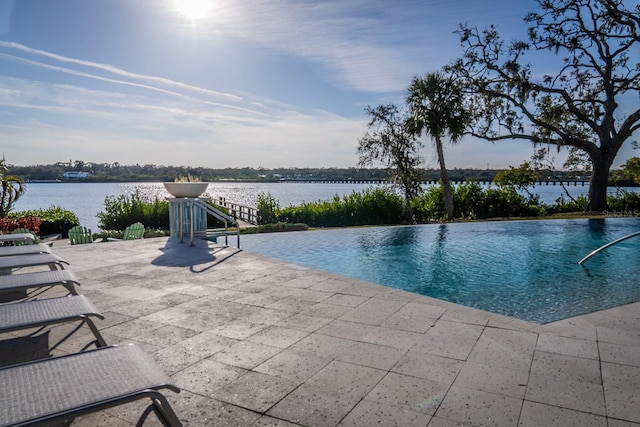 view of swimming pool with a water view and a patio