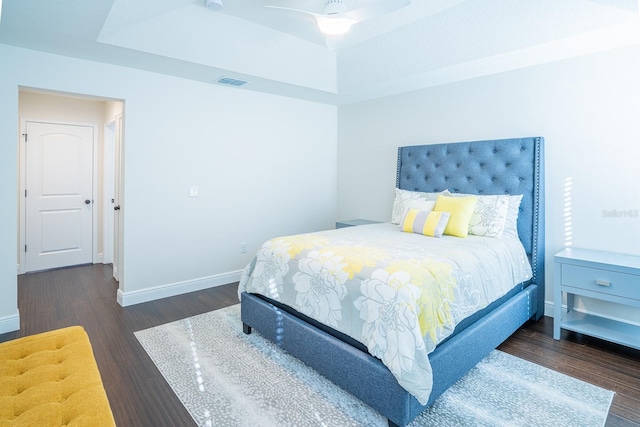 bedroom featuring a raised ceiling and dark wood-type flooring