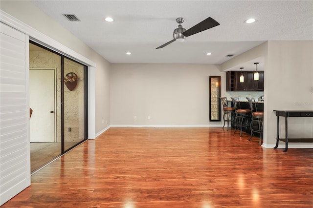 living room with ceiling fan, wood-type flooring, and indoor bar