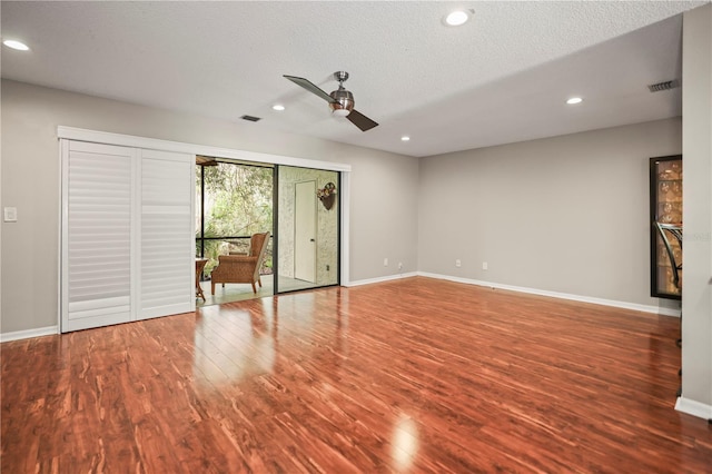 unfurnished living room with a textured ceiling, wood-type flooring, and ceiling fan