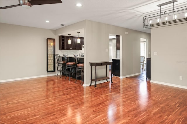 kitchen featuring ceiling fan, a kitchen bar, hardwood / wood-style floors, and dark brown cabinets