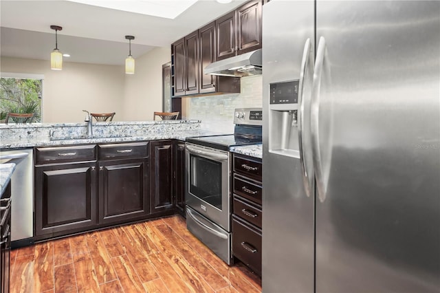 kitchen with decorative light fixtures, light hardwood / wood-style flooring, light stone countertops, and appliances with stainless steel finishes